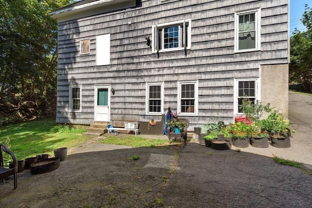 back of house featuring entry steps, a patio area, and a yard