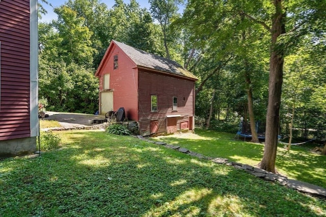 view of side of home featuring a trampoline and a lawn