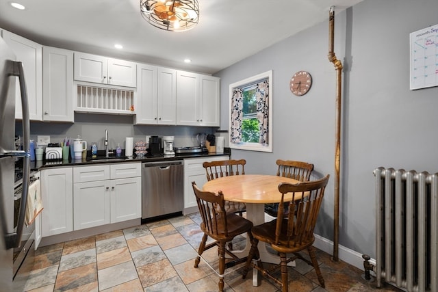 kitchen featuring dishwasher, sink, radiator heating unit, and white cabinetry