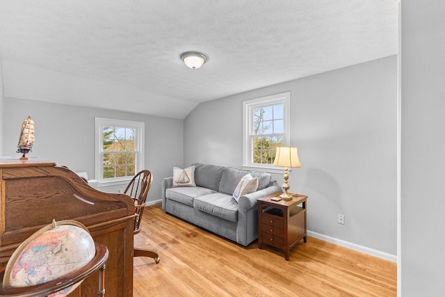 bedroom featuring a textured ceiling, light hardwood / wood-style flooring, and vaulted ceiling