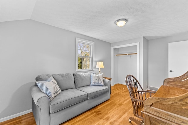 home office with vaulted ceiling, hardwood / wood-style floors, and a textured ceiling