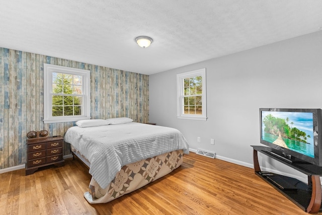 bedroom with a textured ceiling and light hardwood / wood-style flooring