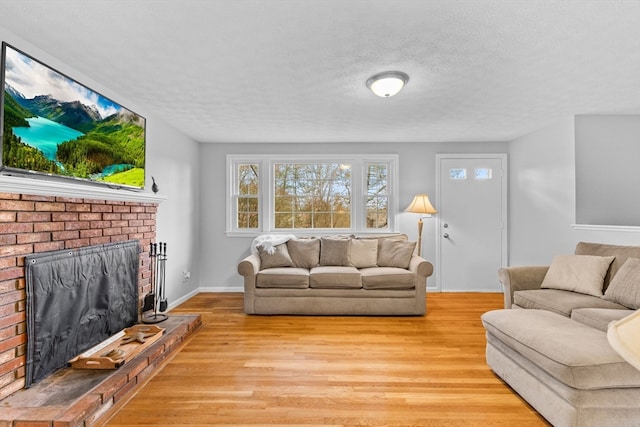 living room with a fireplace, a textured ceiling, and light hardwood / wood-style floors