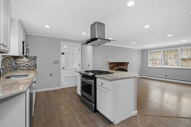 kitchen with island exhaust hood, a sink, decorative backsplash, appliances with stainless steel finishes, and open floor plan