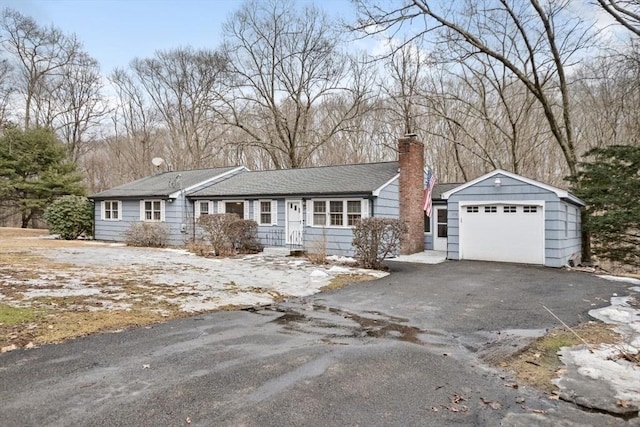 ranch-style house with a chimney, driveway, and an attached garage