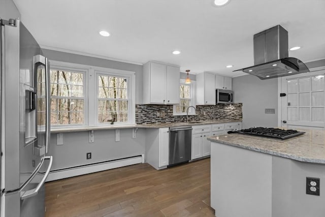 kitchen featuring backsplash, white cabinetry, stainless steel appliances, island range hood, and baseboard heating