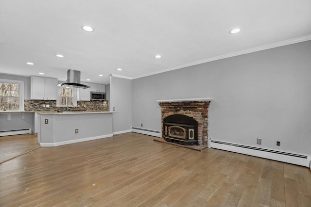 unfurnished living room featuring light wood finished floors, crown molding, and a baseboard heating unit