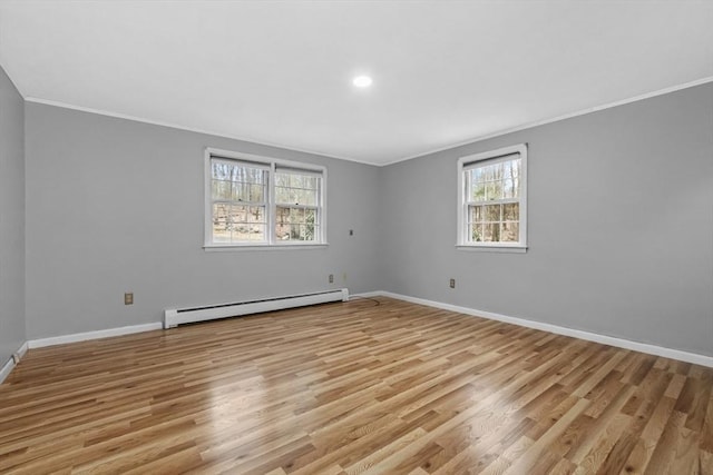 empty room with crown molding, baseboards, a baseboard heating unit, and light wood-style floors