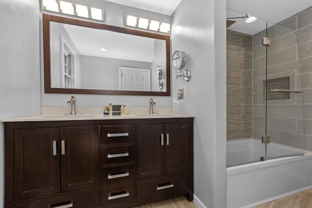 bathroom featuring double vanity, baseboards, bath / shower combo with glass door, and a sink