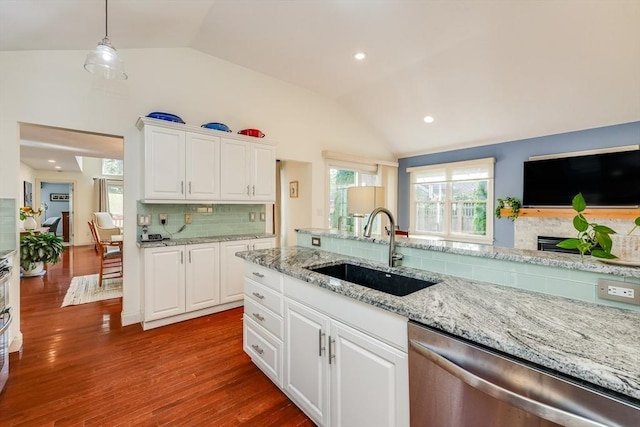 kitchen with sink, white cabinetry, decorative light fixtures, vaulted ceiling, and stainless steel dishwasher