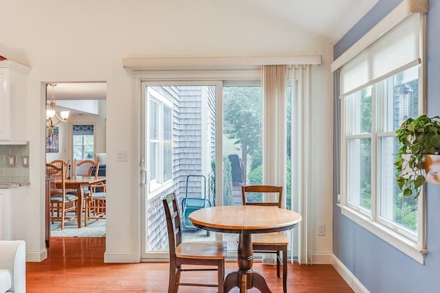 dining area featuring light hardwood / wood-style flooring, a notable chandelier, and vaulted ceiling