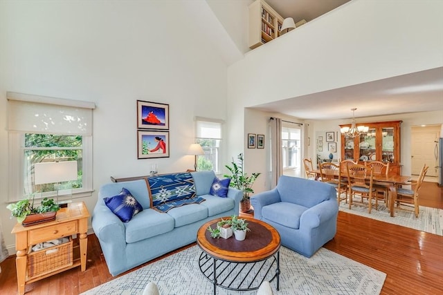 living room with hardwood / wood-style flooring, a towering ceiling, and a chandelier