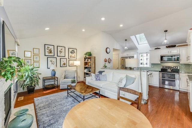 living room with hardwood / wood-style flooring and vaulted ceiling with skylight