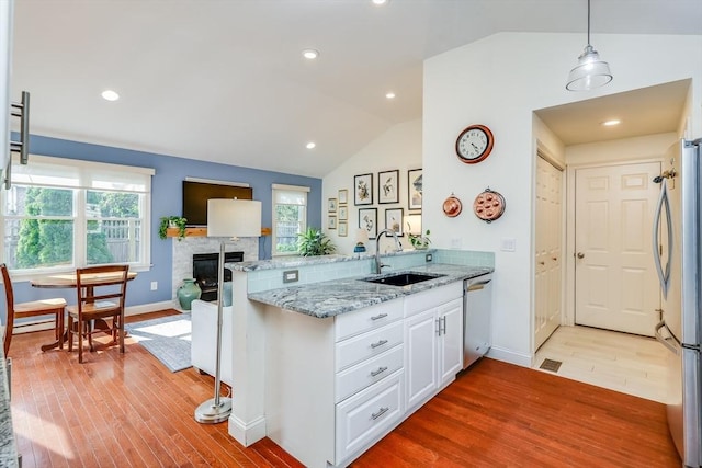 kitchen with appliances with stainless steel finishes, decorative light fixtures, sink, white cabinets, and kitchen peninsula