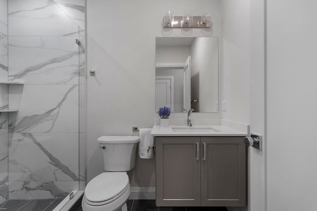 bathroom with tiled shower, vanity, and toilet