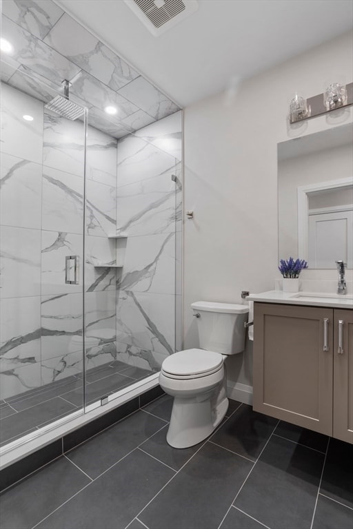 bathroom featuring tile patterned flooring, vanity, toilet, and a shower with shower door