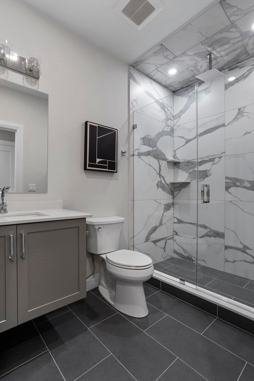 bathroom featuring tile patterned floors, a shower with door, vanity, and toilet