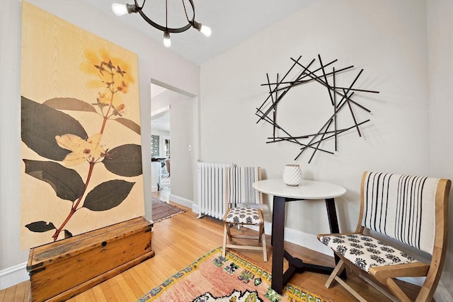 sitting room featuring hardwood / wood-style flooring, a chandelier, and radiator