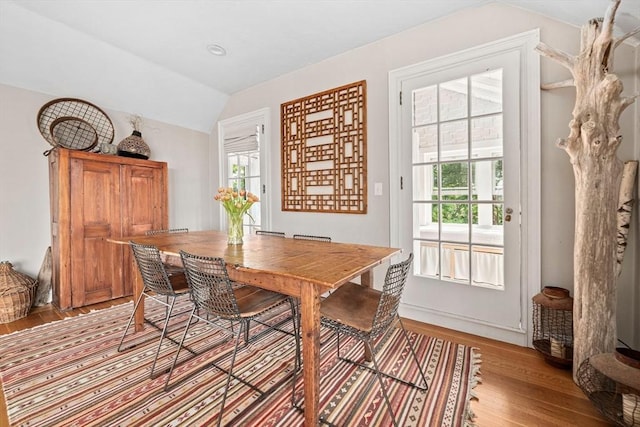 dining space with light hardwood / wood-style floors, a healthy amount of sunlight, and vaulted ceiling