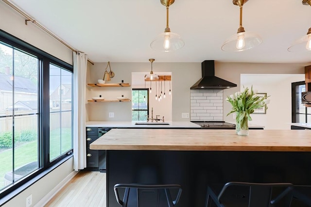 18 Carolina St, Medford, MA 02155 - kitchen featuring butcher block countertops, wall chimney range hood, a sink, light wood-style flooring, and a kitchen bar