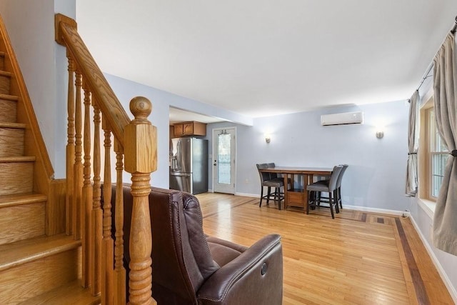 living room with a wall mounted air conditioner and light hardwood / wood-style floors