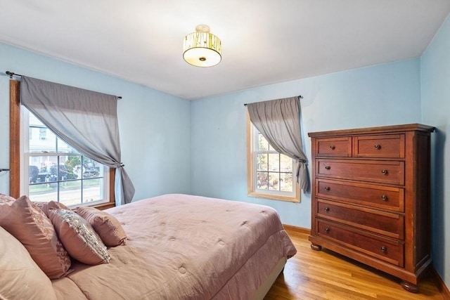 bedroom with light hardwood / wood-style floors and multiple windows