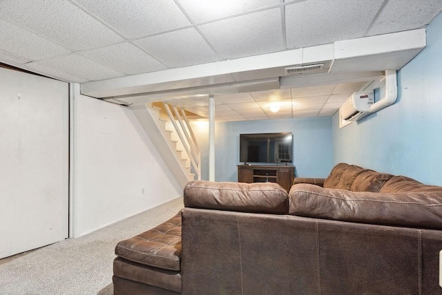 carpeted living room featuring a paneled ceiling and a wall mounted air conditioner