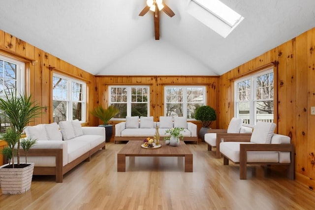 sunroom with ceiling fan, vaulted ceiling with skylight, and a healthy amount of sunlight