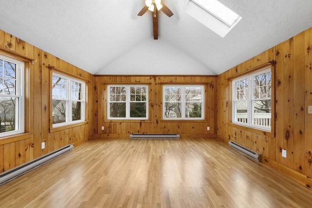 unfurnished sunroom with lofted ceiling with skylight, plenty of natural light, and a baseboard heating unit