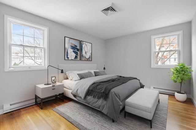 bedroom featuring wood-type flooring and a baseboard heating unit