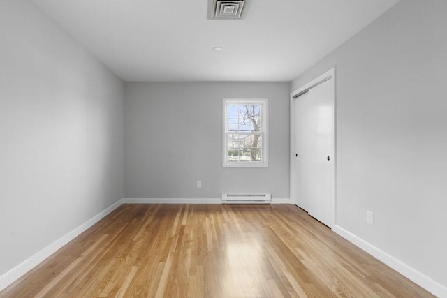 empty room featuring light hardwood / wood-style floors and baseboard heating