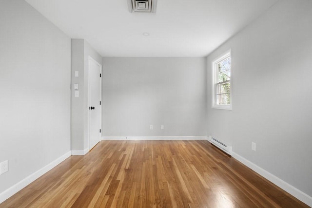 empty room with light hardwood / wood-style flooring and baseboard heating