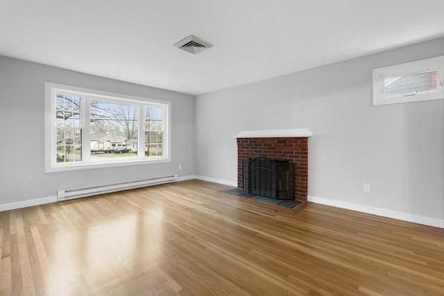 unfurnished living room featuring wood-type flooring, a brick fireplace, and a baseboard heating unit