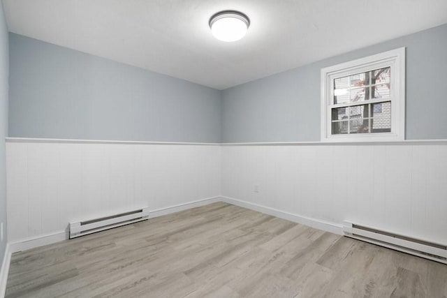 unfurnished room featuring a baseboard radiator and light hardwood / wood-style flooring