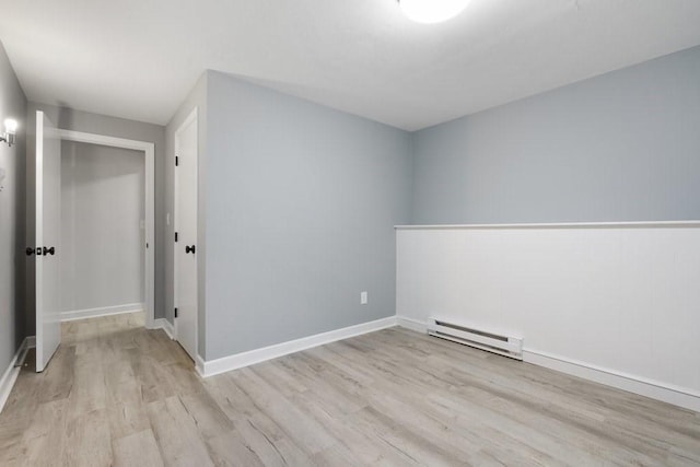 empty room with light hardwood / wood-style flooring and a baseboard heating unit