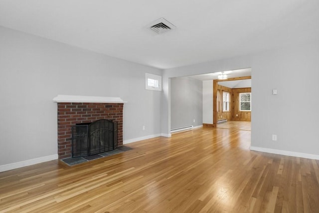 unfurnished living room with light hardwood / wood-style flooring, a baseboard heating unit, and a brick fireplace