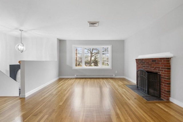 unfurnished living room with a brick fireplace, an inviting chandelier, light wood-type flooring, and a baseboard heating unit