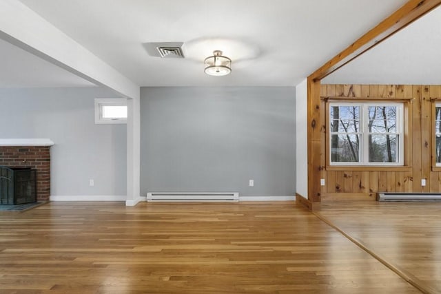 unfurnished living room featuring hardwood / wood-style floors, a brick fireplace, and baseboard heating