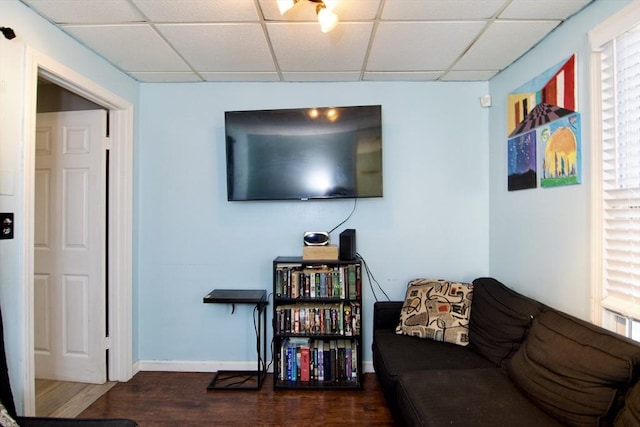 living room with dark hardwood / wood-style flooring and a drop ceiling