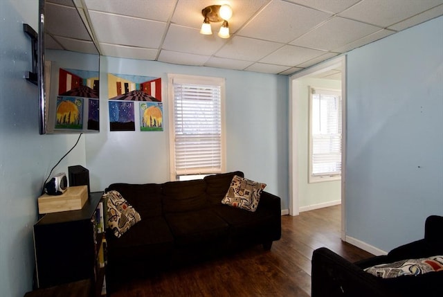 living room featuring a drop ceiling and dark wood-type flooring