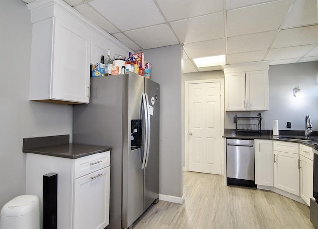 kitchen with a drop ceiling, white cabinetry, sink, and stainless steel appliances