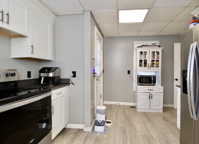 kitchen featuring a drop ceiling, white cabinetry, stainless steel appliances, and light hardwood / wood-style flooring