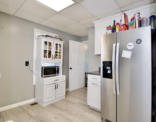 kitchen featuring white cabinetry, a drop ceiling, light hardwood / wood-style floors, and appliances with stainless steel finishes