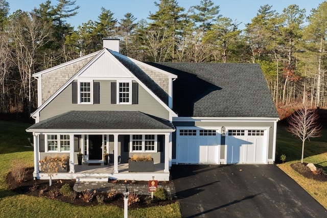 view of front facade with aphalt driveway, a porch, roof with shingles, an attached garage, and a chimney