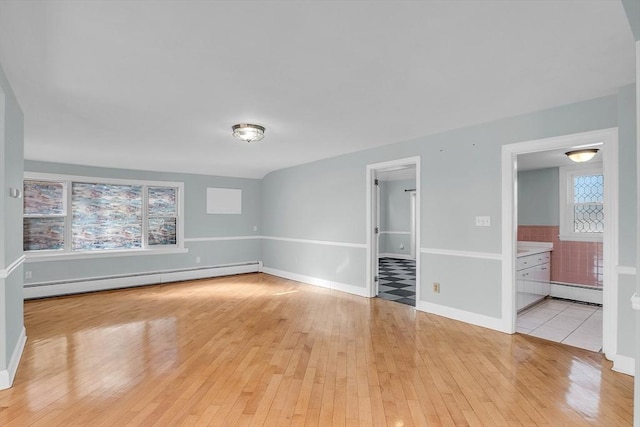 spare room featuring a baseboard radiator and light hardwood / wood-style floors