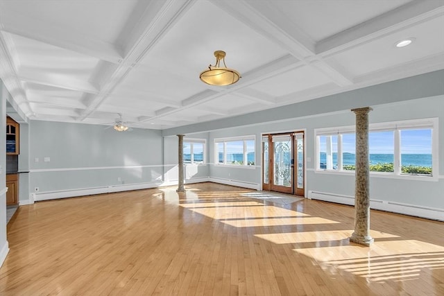 unfurnished living room featuring beamed ceiling, light wood-type flooring, a baseboard radiator, and plenty of natural light