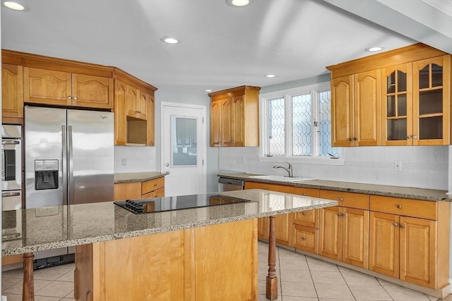 kitchen featuring light tile patterned flooring, sink, light stone countertops, appliances with stainless steel finishes, and a kitchen island