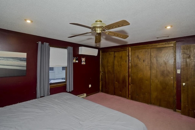 bedroom featuring light colored carpet, a baseboard radiator, a wall unit AC, and a textured ceiling