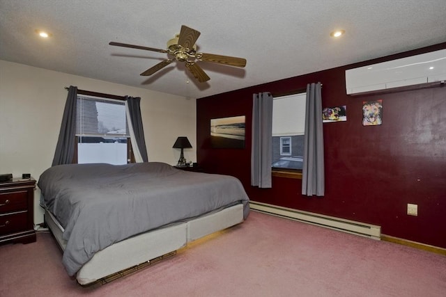 bedroom featuring ceiling fan, a baseboard heating unit, carpet flooring, a wall mounted air conditioner, and a textured ceiling