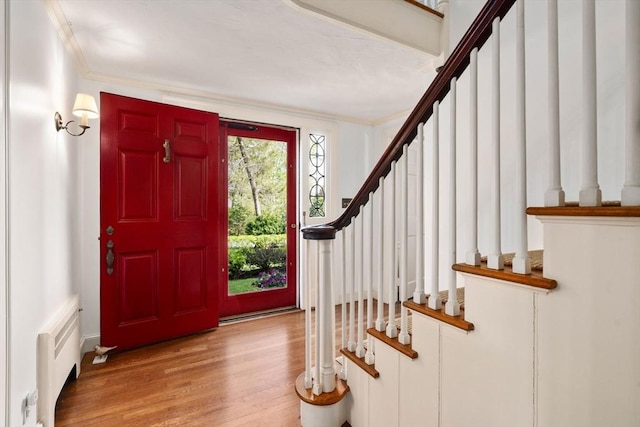 foyer entrance featuring stairway, radiator, crown molding, and wood finished floors